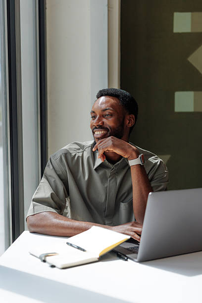 istock Young businessman smiling and looking outside while working on laptop 2221219662