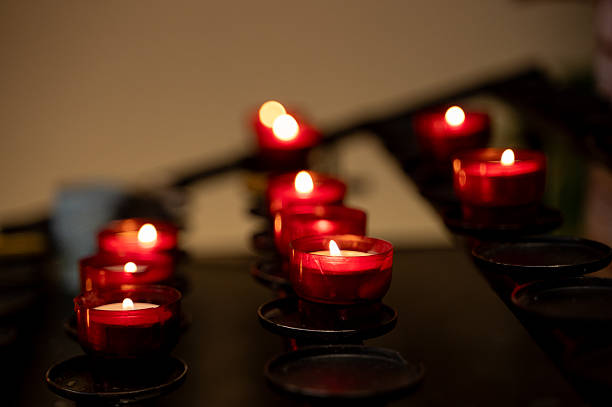 istock Red votive candles burning in dark chapel 2221219889