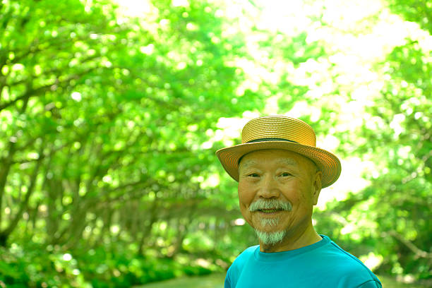 Smiling elderly man enjoying forest bathing in the fresh greenery
