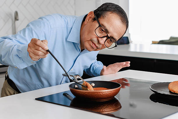 istock Senior man carefully flipping a pancake in the kitchen 2221221934