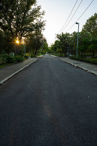 istock Pathway in green tree city public park sunset light with building 2221230462