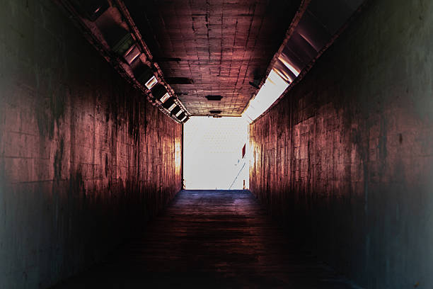 istock Long dark empty tunnel walkway with light at the end. 2221235707