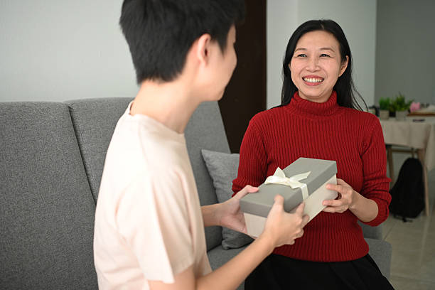 istock Man surprises his mother with gift box. 2221236414