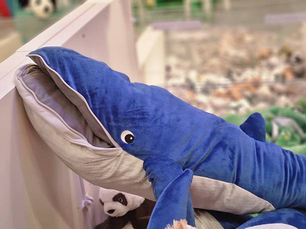 A large, soft, blue whale plush toy with a friendly eye in a store