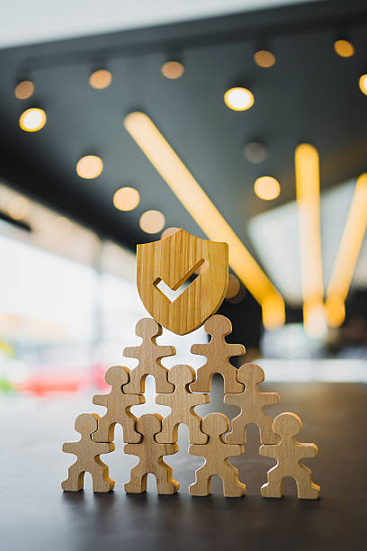 istock Employees form a protective pyramid, topped by the insurance symbol, signifying group insurance as the foundation of their security. 2221244532