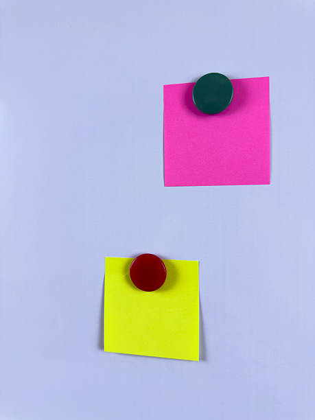 istock Pink and yellow sticky notes secured with magnets on a whiteboard ideal for reminders planning and organization in office school or home environments enhancing efficiency and creativity 2221264617
