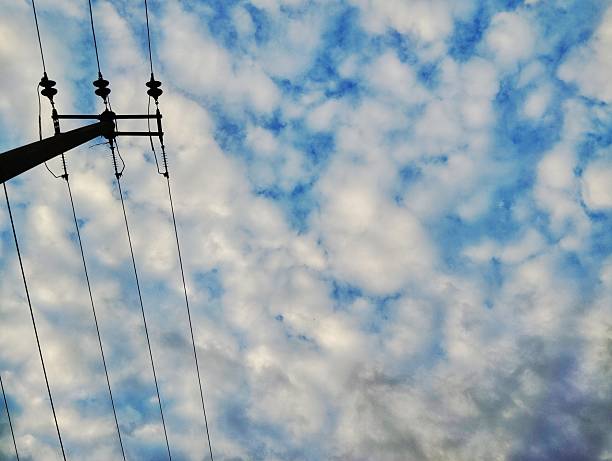 Silhouette of electric pole with beautiful white clouds and blue sky background