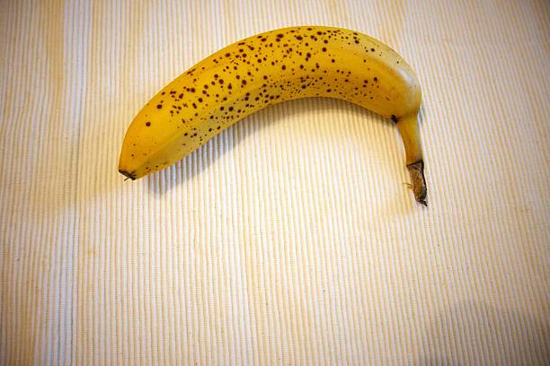 One yellow and brown banana with white background.