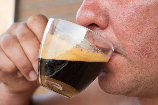 Close-up of a man enjoying a cup of espresso, savoring the rich aroma and flavor