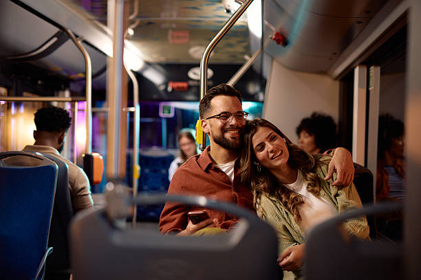 istock Young couple embracing and smiling while traveling by bus at night 2221272589