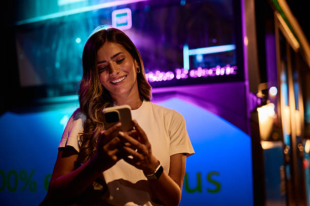 istock Young woman using her smartphone while waiting for the bus at night 2221272714
