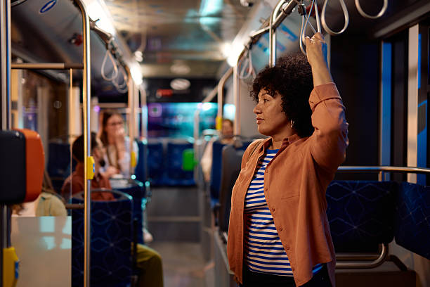 Young woman commuting by bus holding the handle while standing
