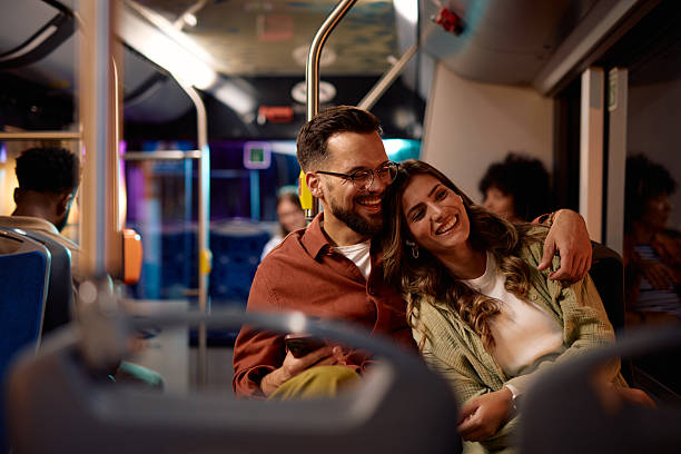 istock Young couple embracing and laughing while riding bus at night 2221272816