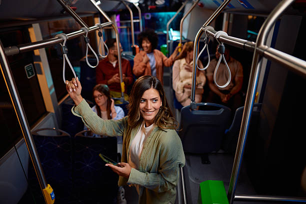istock Young woman standing on a bus while holding onto a handle and using her phone 2221272909