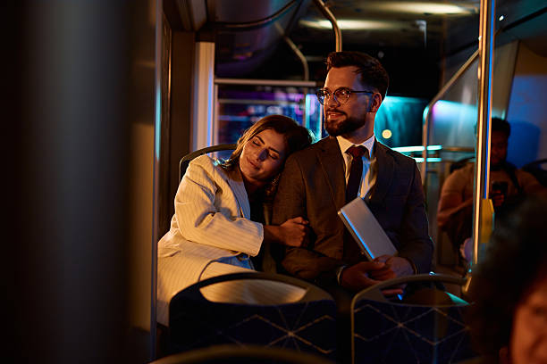 istock Businesswoman sleeping on businessman's shoulder while commuting by bus at night 2221272941