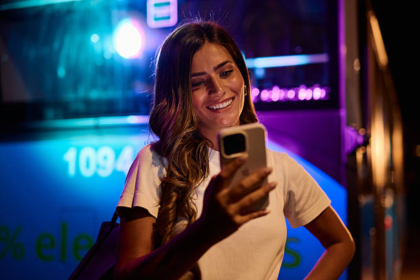 istock Young woman using mobile phone at night near bus 2221273107