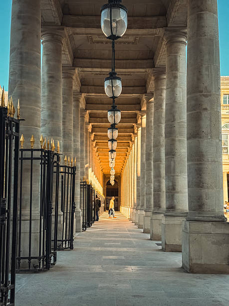 istock Sunlit Colonnade with Repeating Pillars, Hanging Lanterns, and Distant Figure 2221273889