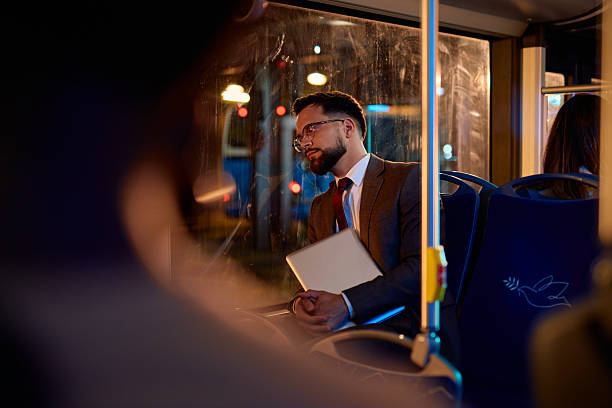 istock Businessman commuting by bus at night holding laptop 2221274946