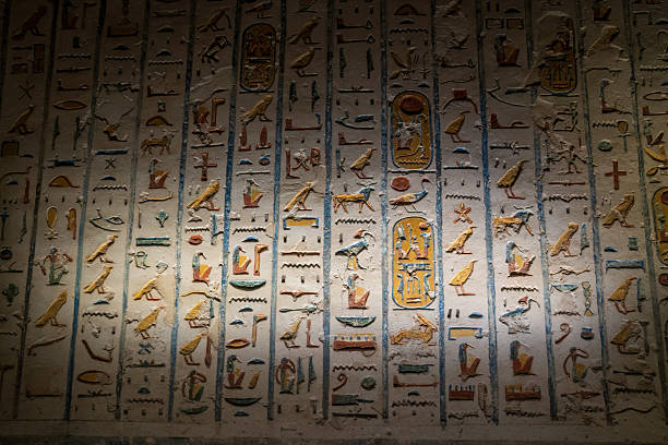 Colorful hieroglyphics preserved on an ancient stone wall lit dramatically, showcasing Egyptian art and language.