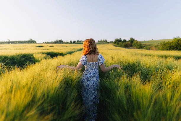 istock Unrecognizable Woman Walking Through Lush Green Wheat Field 2221281009