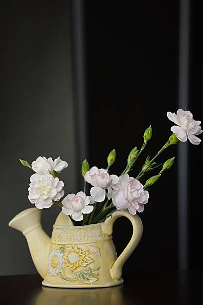 istock Small bouquet of pink carnations in yellow ceramic watering can 2221281990