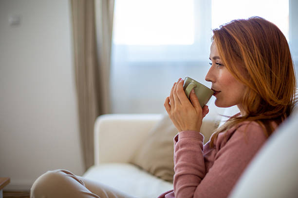 istock Serene woman enjoying a hot beverage on her sofa at home 2221283738