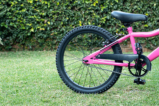 Back wheel of a pink coloured ladies bicycle.