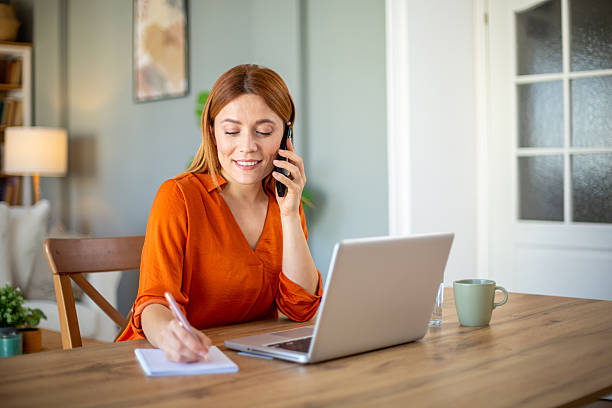 istock Woman working from home talking on phone and taking notes 2221288141
