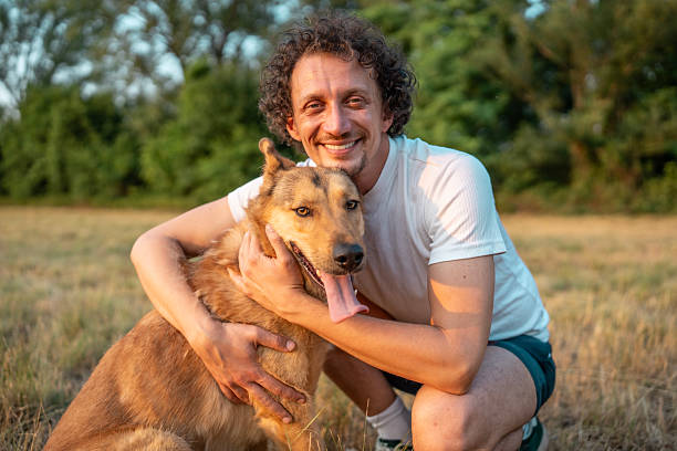 istock Happy Man Hugging His Dog Outdoors in a Sunny Meadow 2221288707