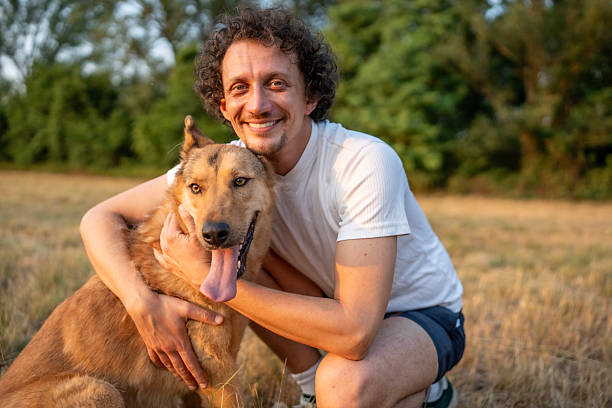 istock Man Smiling with His Dog Outdoors During a Sunny Day in Nature 2221288710