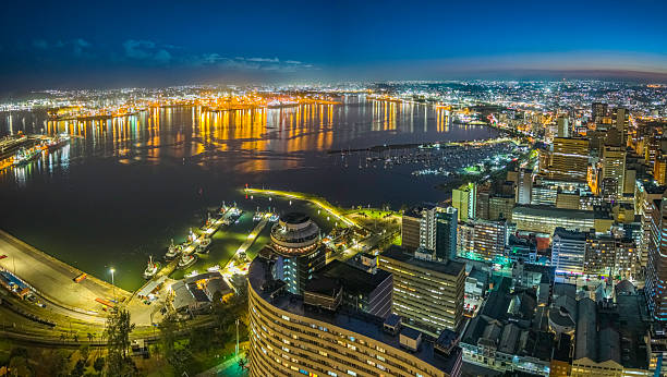 Durban city with the port harbour in the evening, with shipping illuminated as they unload and load the freight cargo. Durban is the third-most populous city in South Africa.