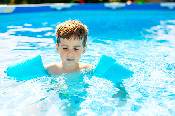 istock Toddler boy with floaters swimming in a pool 2221303953