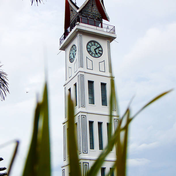 Bukittinggi, Indonesia - Dec 30, 2017: A scenic view of Minangkabau Big Clock (Jam Gadang) and grasses silhouettes.