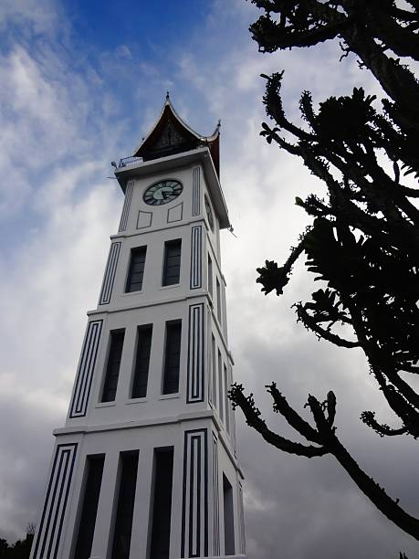 Bukittinggi, Indonesia - Dec 30, 2013: A low angle shot of Minangkabau Big Clock (Jam Gadang) and cactus silhouettes.