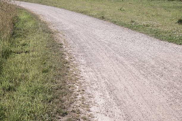 Serene gravel path meanders through lush green fields, offering a tranquil escape for walkers and nature enthusiasts