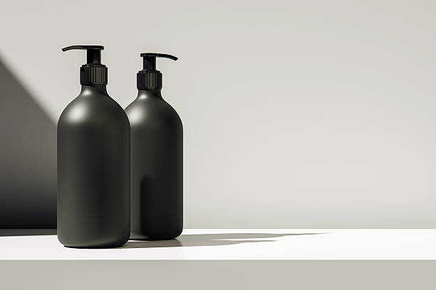 istock Two black pump dispenser bottles on white surface with sunlight and shadow, minimalist packaging mockup for cosmetic or soap product design. 3D Rendering 2221325222