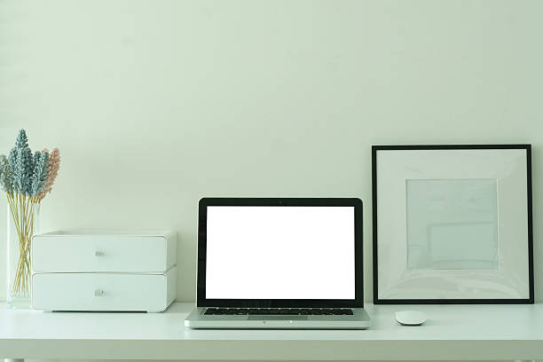 istock Laptop with a blank screen, coffee cup  and picture frame on white desk, for design mockups or editorial use. 2221327372