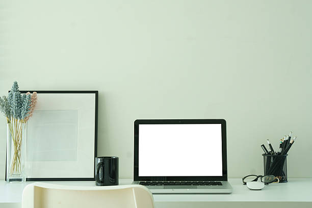 istock Laptop with a blank screen, coffee cup  and picture frame on white desk, for design mockups or editorial use. 2221327375