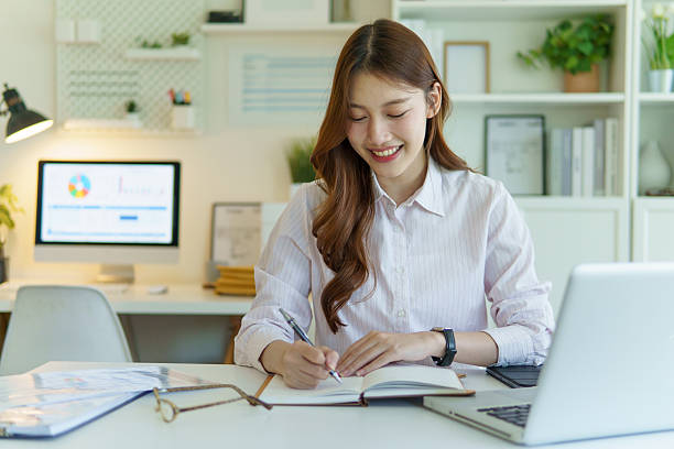 istock Confident female worker jotting down notes or a to-do list in a planner.Confident female worker jotting down notes or a to-do list in a planner. 2221327446