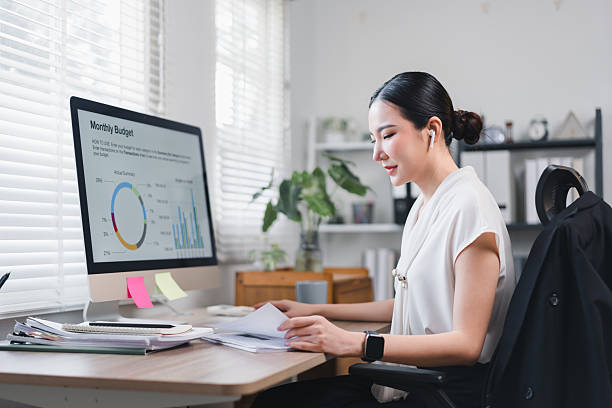 istock Focused Asian Businesswoman Working on Financial Documents at Her Desk With Computer Displaying Monthly Budget Report. 2221332334