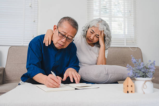 istock Elderly Couple Sitting on Sofa, Discussing and Writing in Notebook With Thoughtful Expression. 2221333580
