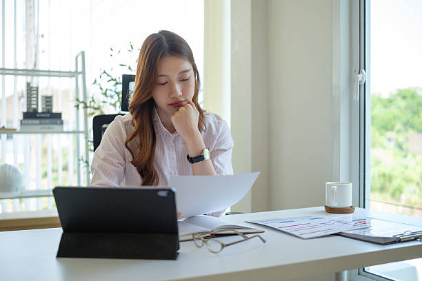 istock Businesswoman deeply focused while reading a printed report at her office desk. 2221334145
