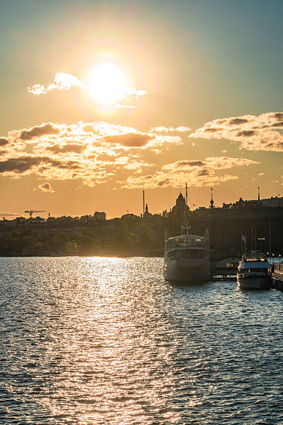 Beautiful sunset over stockholm's skyline with boats moored in the foreground, reflecting the golden light