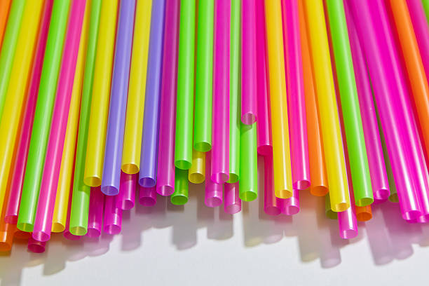 Bright neon plastic drinking straws arranged in various patterns. Ideal for illustrating disposable beverage packaging, fun party decor, or raising awareness about single-use plastic waste. Vivid colors perfect for editorial or commercial use.