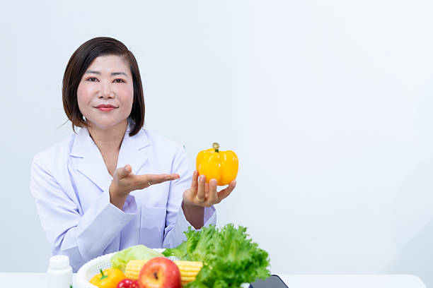 istock Nutritionist holding yellow bell pepper with fresh vegetables on table 2221348196
