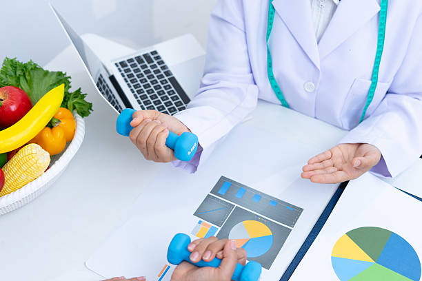 istock Nutritionist discusses healthy eating with client using charts and dumbbells 2221348230