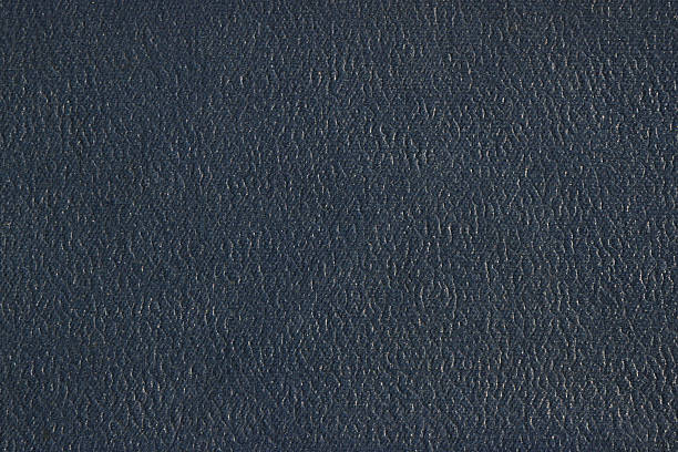 High-resolution macro shot of a dark textured leather book cover, filling the frame. The subtle surface detail and neutral tone make it ideal for use in design mockups, document backgrounds, or conceptual representations of literature, education, or classic bookbinding.