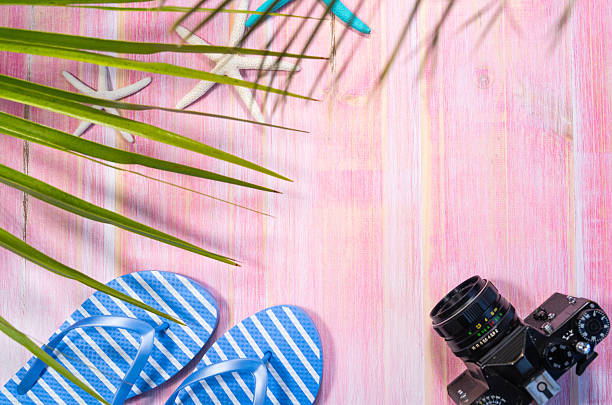 Summer holiday background featuring beach accessories and a vintage camera resting on vibrant pink wooden planks, evoking memories of relaxation and fun