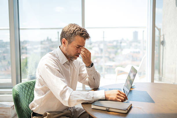 Businessman experiencing stress work at desk with laptop in modern office.