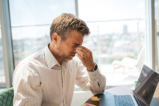 istock Stressed businessman working on laptop in a modern office setting 2221370372